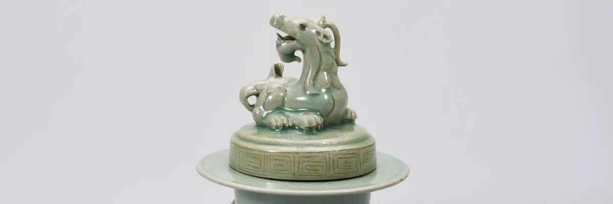 grünliches Objekt in Form eines Drachen auf einem Gefäß