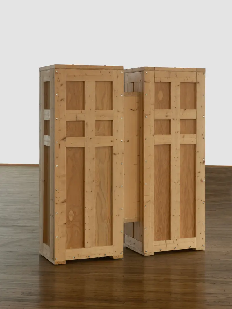 Zu sehen ist eine Skulptur des Künstlers Richard Artschwager, die einer Transportkiste zum Verwechseln ähnlich sieht. Die form besteht aus zwei Korpussen, die flügelartig mit einer Brücke verbunden sind und in dieser doch ungewöhnlichen Form jenen Gegenstand evozieren, die sie vermeintlich verbirgt. 