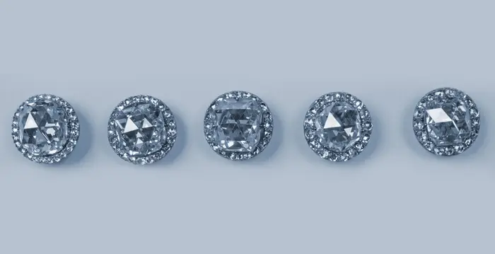 Hier sind 5 Knöpfe zu sehen. In der Mitte der Knöpfe befindet sich eine große Diamantrose. Sie ist von vielen kleinen Diamantrosen umgeben.