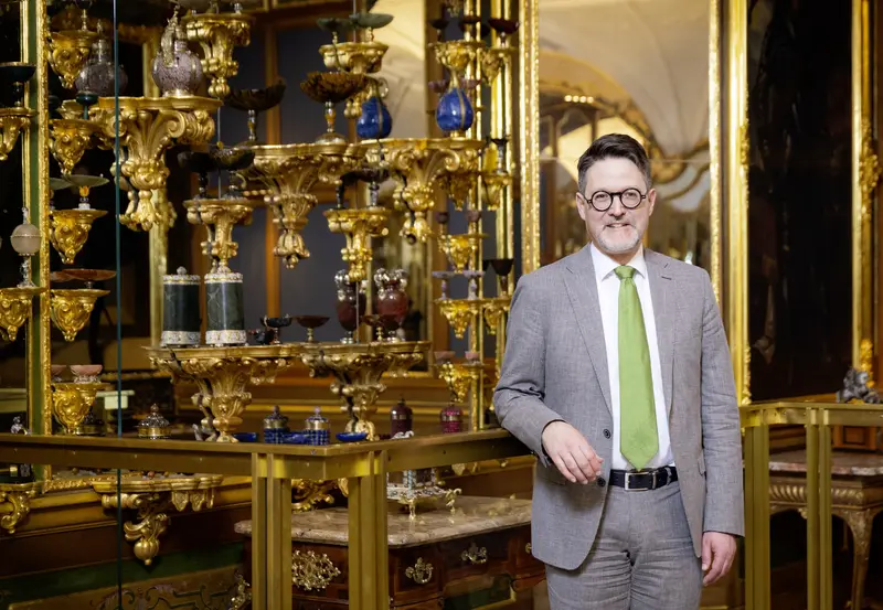 Mann vor einer Wand mit Pretiosen