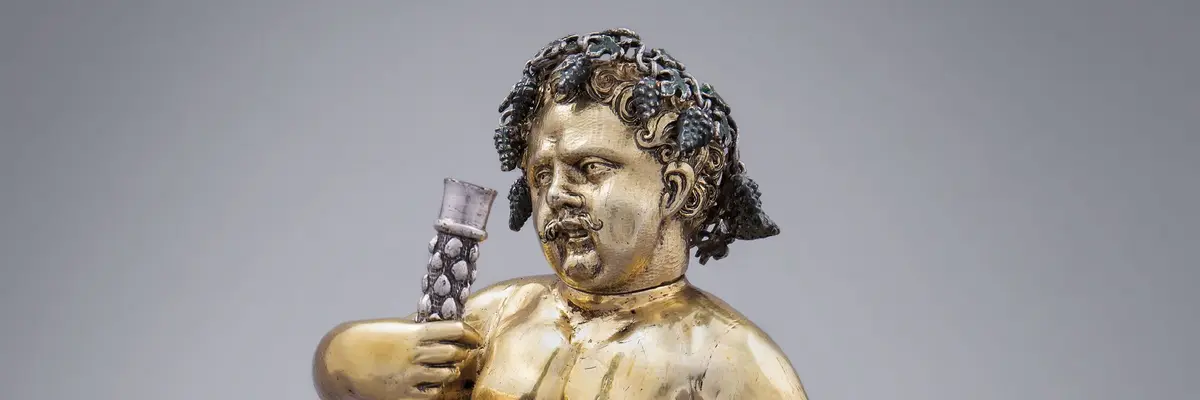 Figur mit einem Glas Wein in der Hand sitzt auf einem Weinfass