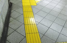 Olaf Holzapfel, "Unbestechliche Archive" - Blatt 6 (gelbe Fliesen, nach links und rechts verzweigend) Gelbe, mit linienförmigen Erhebungen bedeckte Fliesen heben sich als Abzweigung von einem grauen Fliesenboden ab.