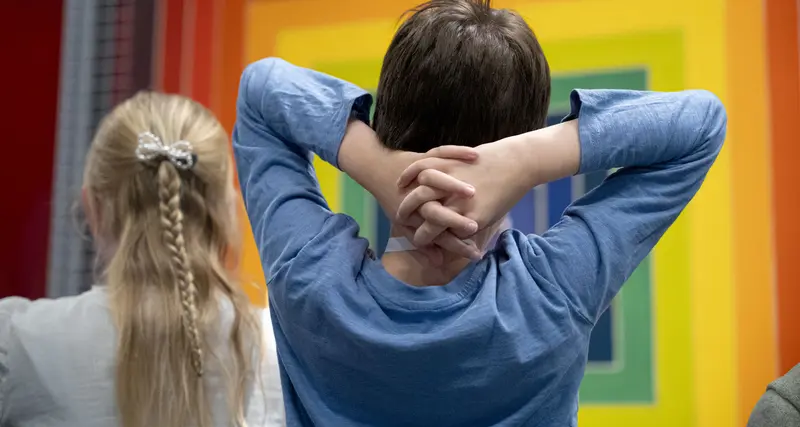 zwei Kinder vor einem Kunstwerk aus Regenbogenfarben