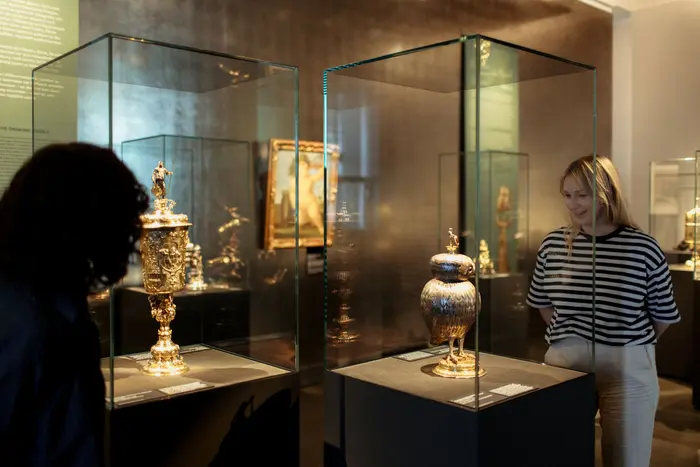 Besucherinnen schauen sich eine Kunstwerke in einer Vitrine an