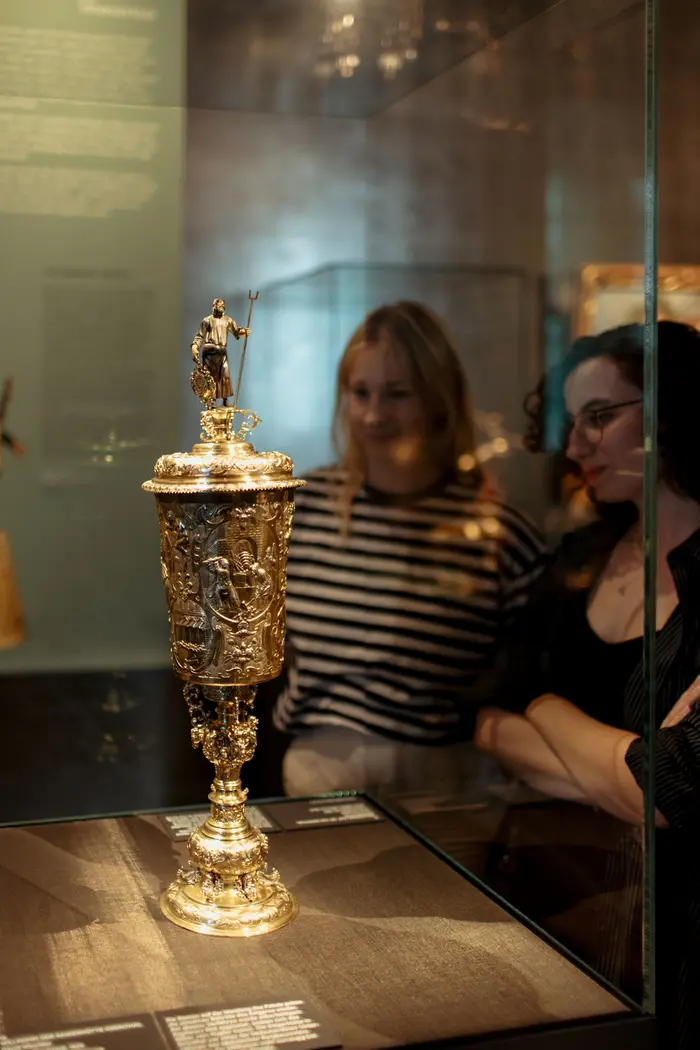 Besucherinnen schauen sich Kunstwerke in einer Vitrine an