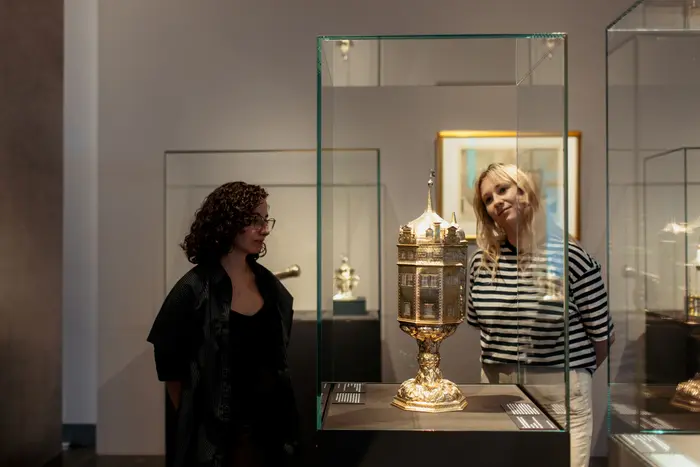 Besucherinnen schauen sich Kunstwerke in einer Vitrine an