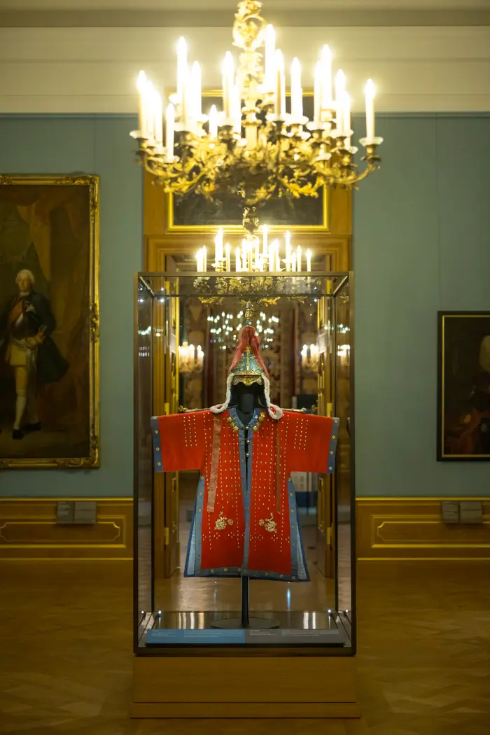 rotes Kostüm in einer Vitrine in einem prächtigen Raum