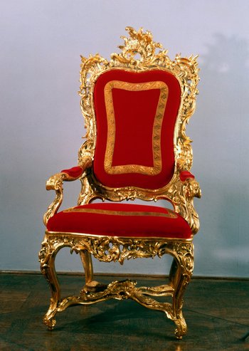 ein goldener Audienzstuhl mit rotem Samtbezug