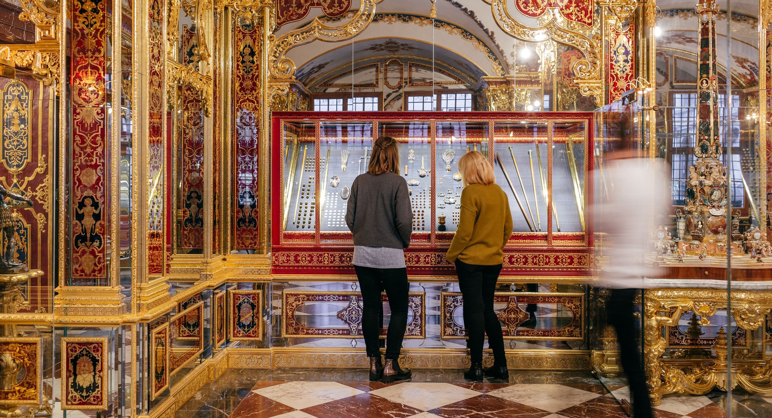 Besucher, die sich kleine Objekte in Vitrine anschauen