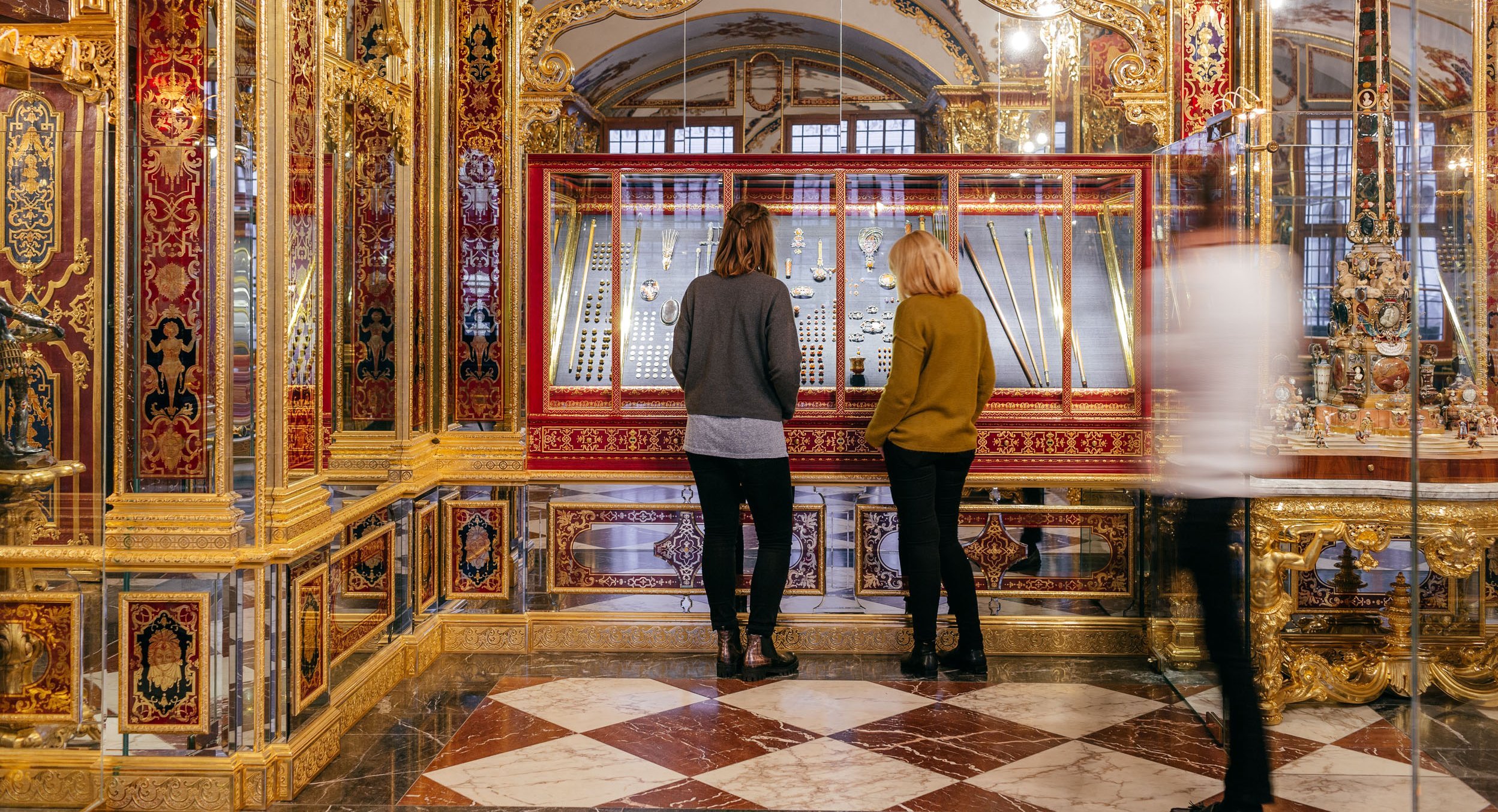 Besucher, die sich kleine Objekte in Vitrine anschauen