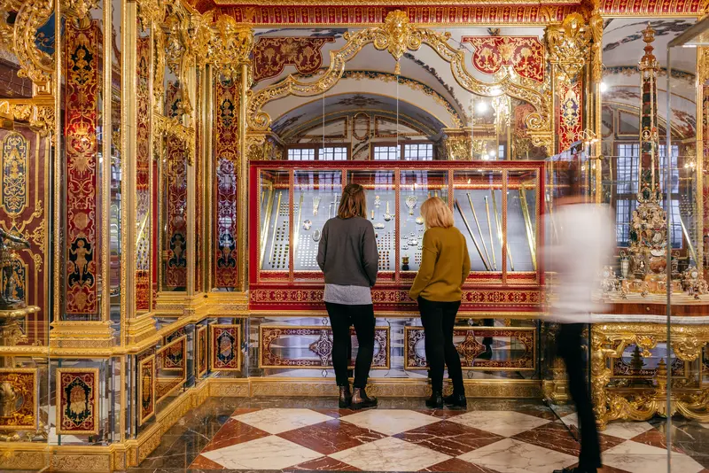Besucher, die sich kleine Objekte in Vitrine anschauen