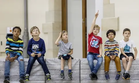 Kinder sitzen auf einer Bank im Museum