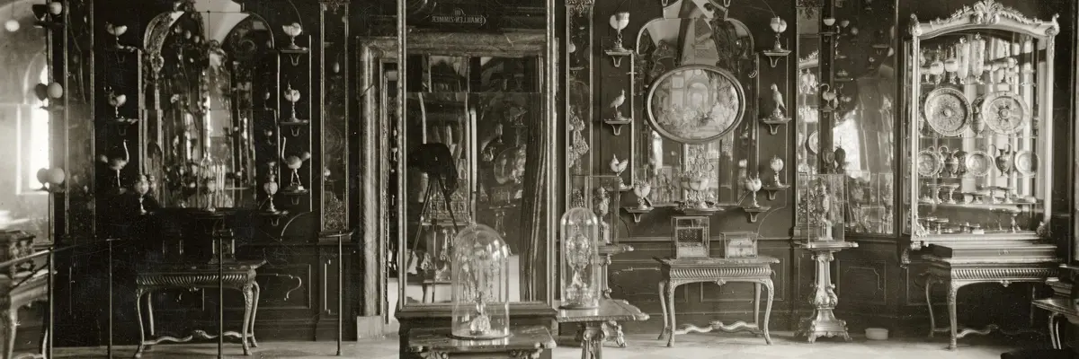 Auf diesem historischen Foto ist die Raumausstattung des Emailzimmers von 1930 zu sehen. Der Mittelpfeiler ist verspiegelt. Die Wände sind mit Holzpanelen, Spiegeln und zahlreichen Kunstobjekten bestückt.