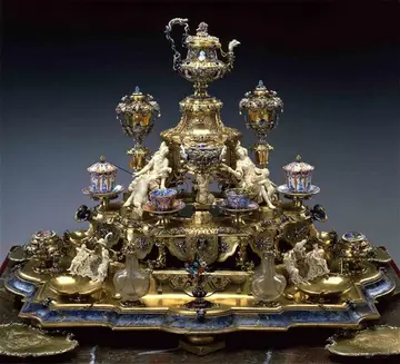Pyramide mit Trinkgefäßen, Figuren sitzen dazwischen