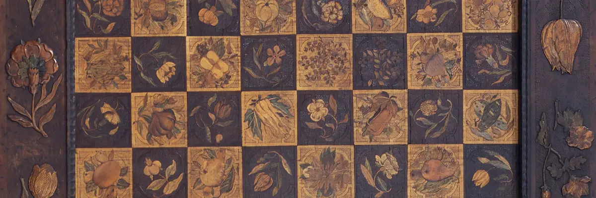 Diese Abbildung zeigt ein Brettspiel aus Holz. Es ist mit kunstvollen Einlegearbeiten versehen.